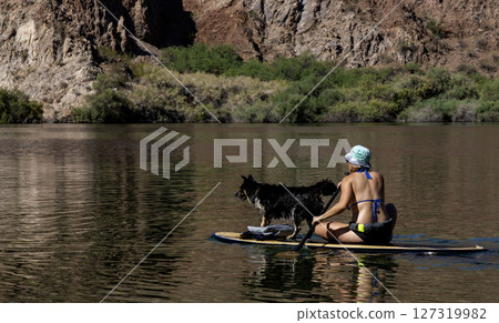Women Enjoying a Peaceful Day Paddleboarding With a Dog at the Lake Women Enjoying a Peaceful Day Paddleboarding With a Dog at the Lake 127319982