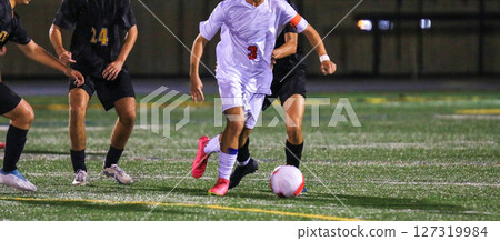 Young Athlete Dribbles Soccer Ball in Night Match 127319984