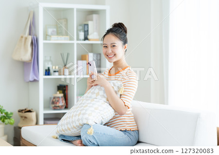 A young woman using a smartphone in the living room 127320083