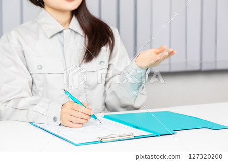 Woman in work clothes writing in a binder 01 Woman in work clothes writing in a binder 01 127320200