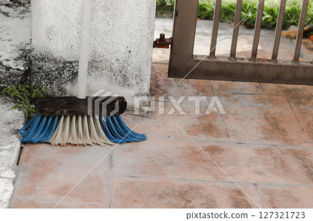 A cleaning broom leaning against a wall outdoors A cleaning broom leaning against a wall outdoors 127321723