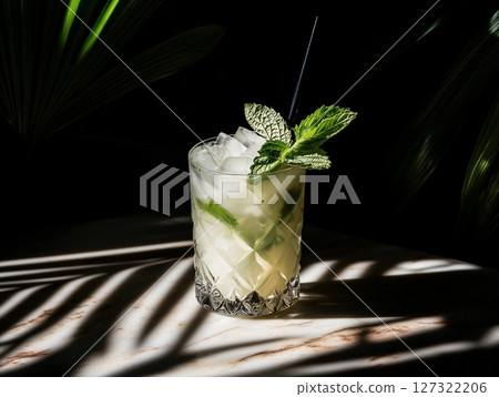 Refreshing cocktail in glass with mint and lime on dark background with plant shadows. Refreshing cocktail in glass with mint and lime on dark background with plant shadows. 127322206