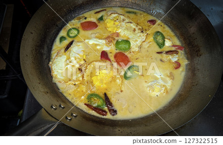 Rich Spicy Egg soup Dish with coconut milk and Vegetables in Rustic Pan, for illustrating authentic home cooking meals Rich Spicy Egg soup Dish with coconut milk and Vegetables in Rustic Pan, for illustrating authentic home cooking meals 127322515
