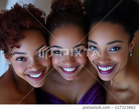 Top view of three smiling African American women with tied-up hair, enjoying a happy moment. Top view of three smiling African American women with tied-up hair, enjoying a happy moment. 127323662