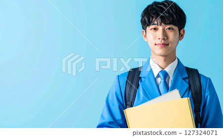 a confident Asian male student wearing a blue uniform and backpack, holding books against a soft blue background. Perfect for school ads, educational posters, and learning materials 127324071