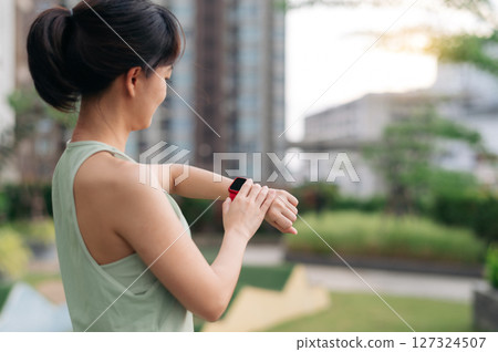 Content asian woman in 30s check pulse and heart rate result on smartwatch during urban city sunset workout. healthy lifestyle exercise for fitness wellness with technology wristwatch healthcare Content asian woman in 30s check pulse and heart rate result on smartwatch during urban city sunset workout. healthy lifestyle exercise for fitness wellness with technology wristwatch healthcare 127324507