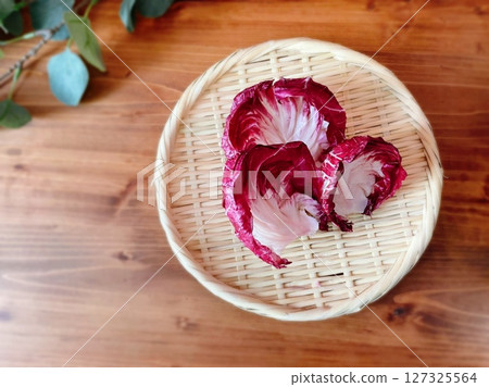 帶有木紋背景的竹籃上的菊苣葉 帶有木紋背景的竹籃上的菊苣葉 127325564