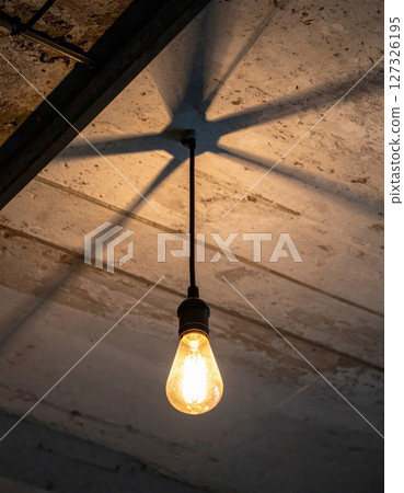 Warm Light from Edison Bulb Hanging in Industrial Interior 127326195