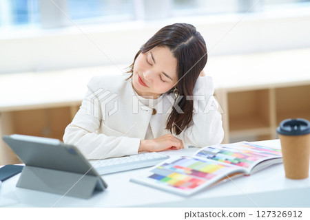 A woman looking tired while working on a computer 127326912