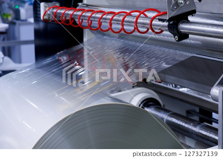 plastic packaging film on the automatic packing machine in food product factory. industrial and technology concept. 127327139