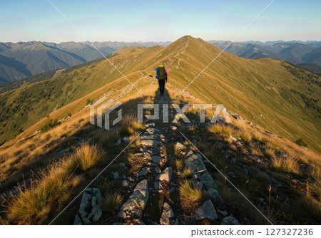 Backpackers Shadow Stretching Across Rocky Mountain Ridge at Sunset Adventure 127327236