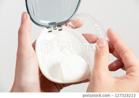 holding a professional orthodontic dental removable brace or removable invisible aligner. Demonstration of modern methods of teeth alignment holding a professional orthodontic dental removable brace or removable invisible aligner. Demonstration of modern methods of teeth alignment 127328213
