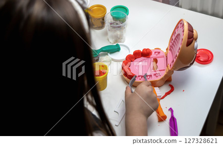 A child plays dentist and makes teeth out of plasticine 127328621
