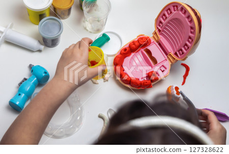 A child plays dentist and makes teeth out of plasticine 127328622