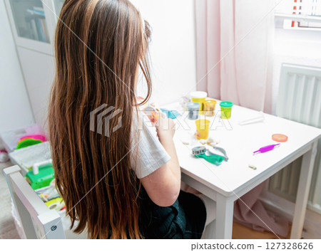 Little girl with long brown hair playing with plasticine 127328626