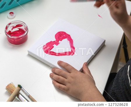 The child paints a red heart 127328628