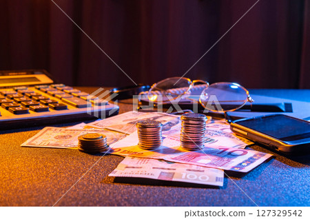 Financial workspace with coins, money, calculator and glasses. Glasses and calculator on the table with money. Finance and accounting. 127329542