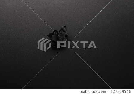 Crumpled sheet on the table. Black crumpled sheet of paper on the table. Black sheet on a black table. View from above. Crumpled sheet on the table. Black crumpled sheet of paper on the table. Black sheet on a black table. View from above. 127329546