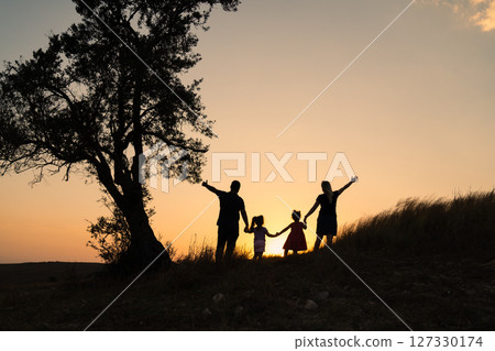 Happy family silhouette standing on against beautidul sunset view. 127330174