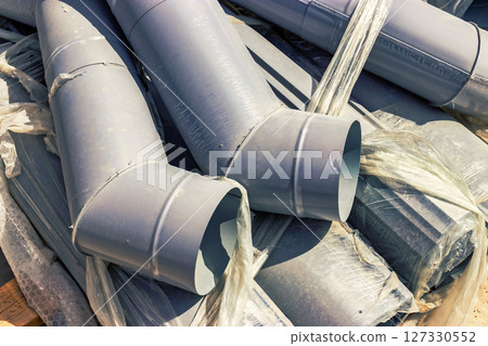 Pipe elements for the installation of roof drainage and rainwater drainage at the construction site. Materials are stored for the installation of a storm water drainage system. Pipe elements for the installation of roof drainage and rainwater drainage at the construction site. Materials are stored for the installation of a storm water drainage system. 127330552