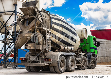 Concrete mixer truck in front of a concrete batching plant, cement factory. Loading concrete mixer truck. Close-up. Delivery of concrete to the construction site. Monolithic concrete works. 127330593