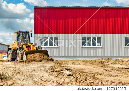 A large front loader pours sand into a pile at a construction site. Transportation of bulk materials. Construction equipment. Bulk cargo transportation. Excavation. 127330615