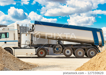Large dump truck near the concrete factory. Car tonar for transportation of heavy bulk cargo. Provision of crushed stone and gravel for concrete production. Large dump truck near the concrete factory. Car tonar for transportation of heavy bulk cargo. Provision of crushed stone and gravel for concrete production. 127330620