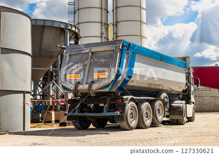 Large dump truck near the concrete factory. Car tonar for transportation of heavy bulk cargo. Provision of crushed stone and gravel for concrete production. 127330621