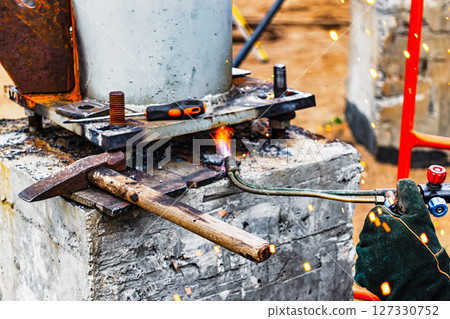 Worker cutting metal plate by Gas Cutting Torch at a construction site. Installation of a metal structure. Close-up. The welder performs the installation of metal structures. Sparks from welding. Worker cutting metal plate by Gas Cutting Torch at a construction site. Installation of a metal structure. Close-up. The welder performs the installation of metal structures. Sparks from welding. 127330752