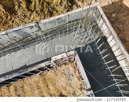 Monolithic reinforced concrete foundations or grillages for the construction of a large modern residential building. Rostverk at the construction site. Foundation for the building. View from above. 127330765