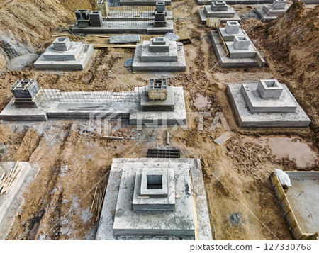 Monolithic reinforced concrete foundations or grillages for the construction of a large modern residential building. Rostverk at the construction site. Foundation for the building. View from above. Monolithic reinforced concrete foundations or grillages for the construction of a large modern residential building. Rostverk at the construction site. Foundation for the building. View from above. 127330768