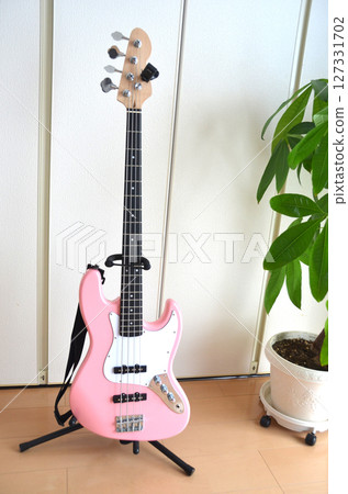 Electric guitar leaning against the living room, pink bass guitar 127331702