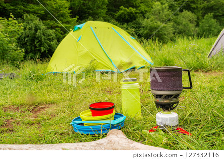 Camping utensils and kitchen. Camping camp with tents and utensils. Camping kitchen against the background of a tent. Cooking outdoors. Camping utensils and kitchen. Camping camp with tents and utensils. Camping kitchen against the background of a tent. Cooking outdoors. 127332116