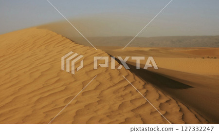 Sand blowing over sand dunes in wind 127332247