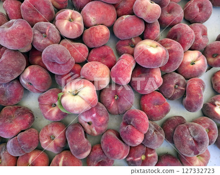 Vibrant and ripe flat fig peaches are abundantly arranged at a bustling market in Spain, showcasing their smooth texture and appealing colors. These Paraguay variety fruits invite shoppers. Vibrant and ripe flat fig peaches are abundantly arranged at a bustling market in Spain, showcasing their smooth texture and appealing colors. These Paraguay variety fruits invite shoppers. 127332723
