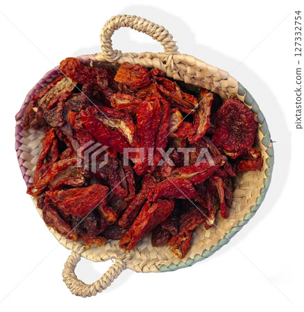 A rustic wicker basket filled with sun dried tomatoes captures the essence of a farmers market in Spain, showcasing local produce under the warm sun. 127332754