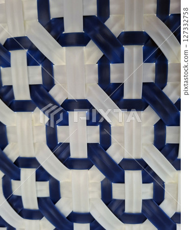 Wicker chair displays a detailed texture with a geometric pattern, showcasing a blend of blue and white elements. This texture adds a unique touch to interior spaces, perfect for modern design. 127332758