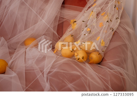 Close-up of fresh lemons on soft white tulle with gentle light in elegant classic interior Close-up of fresh lemons on soft white tulle with gentle light in elegant classic interior 127333095