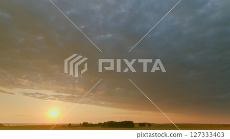Time lapse. A stunningly beautiful sunset stretches over the expansive fields, featuring dramatic clouds Time lapse. A stunningly beautiful sunset stretches over the expansive fields, featuring dramatic clouds 127333403