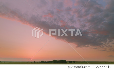 Time lapse. A breathtaking, stunning sunset can be seen over vast, rolling fields adorned with fluffy clouds 127333410