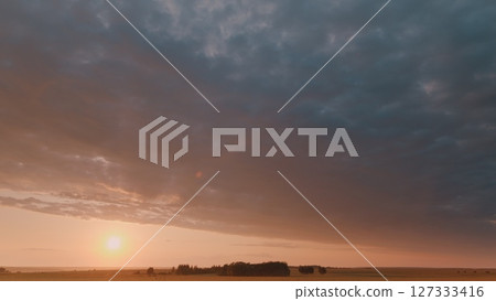 Time lapse. Witness a stunning sunrise lighting up a serene landscape with dramatic clouds in the sky Time lapse. Witness a stunning sunrise lighting up a serene landscape with dramatic clouds in the sky 127333416