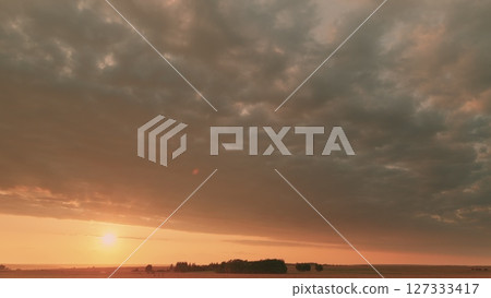 Time lapse. A stunningly beautiful sunset over expansive fields set against a cloudy sky backdrop Time lapse. A stunningly beautiful sunset over expansive fields set against a cloudy sky backdrop 127333417