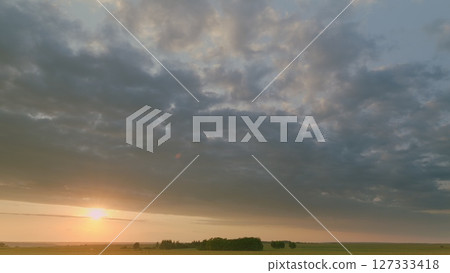 Time lapse. Witness a stunning sunset illuminating green fields and cloudy skies, inspiring peace at dusk 127333418