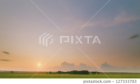 Time lapse. A Serene Sunset Over Beautifully Lush Green Fields Creates an Inspiring and Peaceful Atmosphere 127333783