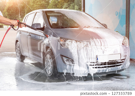 Man cleaning car. Spray hose foam soap. Car wash water shine exterior. Man cleaning car. Spray hose foam soap. Car wash water shine exterior. 127333789