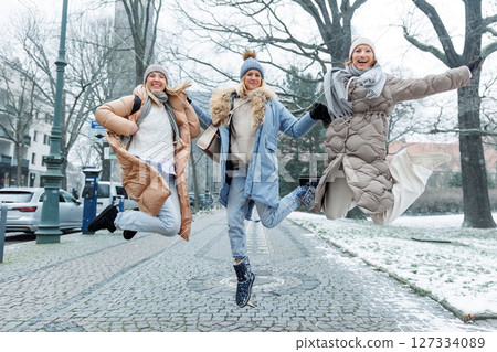 Three cheerful young adult women friend walk Magdeburg street old european uk german town city street enjoy having fun laughing cold winter day together. Female persons friendship celebration weekend 127334089