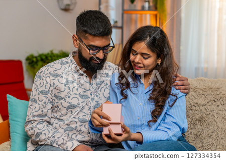 Indian family couple man woman reacting to surprise gift, emotional excited moment of happiness Indian family couple man woman reacting to surprise gift, emotional excited moment of happiness 127334354