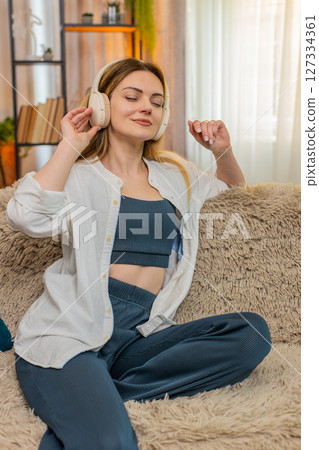 Adult woman listening to music on headphones at home eyes closed enjoying peaceful relaxing moment Adult woman listening to music on headphones at home eyes closed enjoying peaceful relaxing moment 127334361