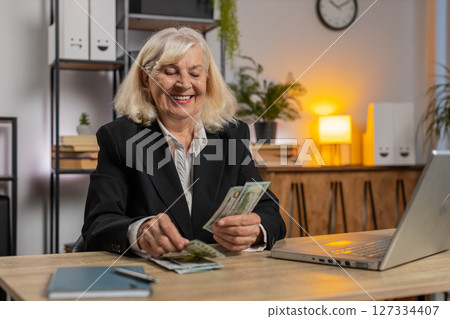 Excited senior businesswoman counting cash money dollar checking salary enjoy richness at workplace Excited senior businesswoman counting cash money dollar checking salary enjoy richness at workplace 127334407