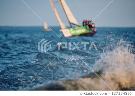 Sailing regatta in the Gulf of Finland at sunset, sailing yacht competing in a race, splashing water from under the boat, teamwork, board the boat 127334555